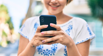 Fototapeta premium Young latin tourist girl on vacation smiling happy using smartphone at the city.