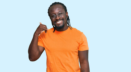 Handsome young african american man wearing casual clothes smiling doing phone gesture with hand and fingers like talking on the telephone. communicating concepts.