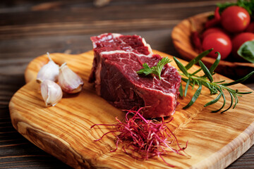 Fresh raw flank steak on the very nice rustikal wooden plate. Old wooden background with copy space for text.