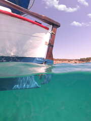 Underwater split photo of traditional wooden fishing boat in Aegean island, with emerald clear sea,...