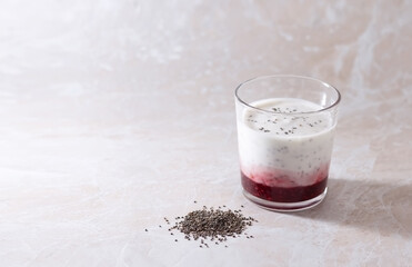 Homemade fermented milk drink with chia seeds and berries in a glass of kefir on a light background. Place for your text.