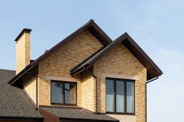 New brick house and metal rood against blue sky