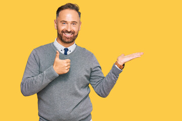 Handsome middle age man wearing business clothes showing palm hand and doing ok gesture with thumbs up, smiling happy and cheerful
