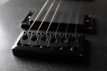 A close-up rusty bridge serves to secure the strings to an electric guitar. Black electric guitar...