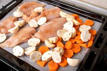 Chicken fillet and chopped vegetables close-up. Carrots, mushrooms and meat on a baking tray. Close up photo of food. Appetizing background.