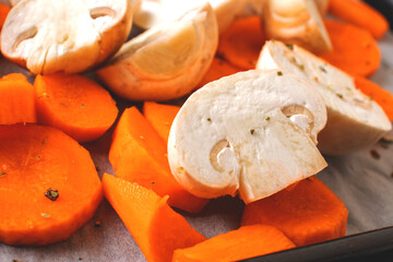 Sliced vegetables close-up. Carrots and mushrooms in pieces on parchment paper. Close-up photo of food.