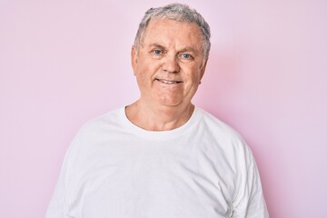 Senior grey-haired man wearing casual white tshirt looking positive and happy standing and smiling with a confident smile showing teeth