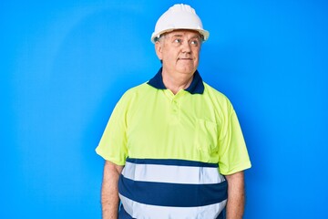 Senior grey-haired man wearing worker reflective t shirt and hardhat looking to side, relax profile pose with natural face and confident smile.