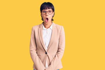 Obraz premium Young brunette woman with short hair wearing business jacket and glasses afraid and shocked with surprise expression, fear and excited face.