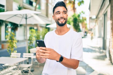 Young arab man smiling happy using smartphone at the city.