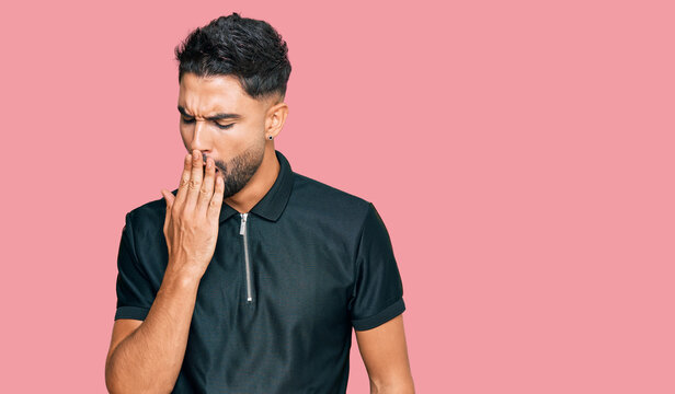 Young man with beard wearing sportswear bored yawning tired covering mouth with hand. restless and sleepiness.