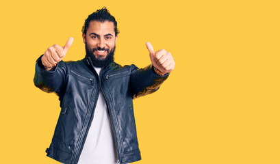 Young arab man wearing casual leather jacket approving doing positive gesture with hand, thumbs up smiling and happy for success. winner gesture.