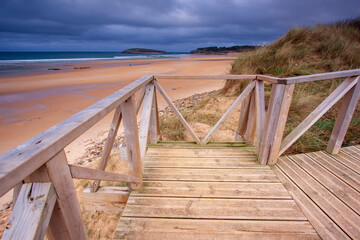 wooden bridge over the sea, dunes of sand. Atlantic Ocean 