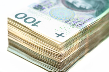 A pile of stacked 100 Polish zloty paper banknotes, isolated on a white background.