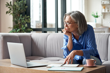 Senior mature older woman watching business training, online webinar on laptop computer remote...