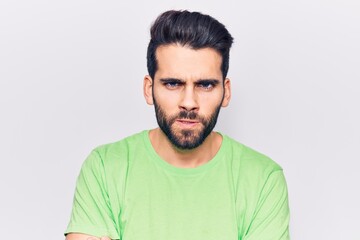 Young handsome man with beard wearing casual t-shirt skeptic and nervous, disapproving expression on face with crossed arms. negative person.
