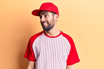 Young handsome man with beard wearing baseball cap and t-shirt looking to side, relax profile pose with natural face and confident smile.