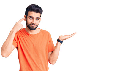 Young handsome man with beard wearing casual t-shirt confused and annoyed with open palm showing copy space and pointing finger to forehead. think about it.