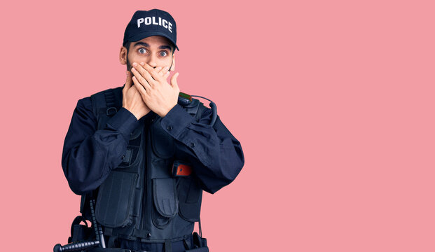 Young handsome man with beard wearing police uniform shocked covering mouth with hands for mistake. secret concept.
