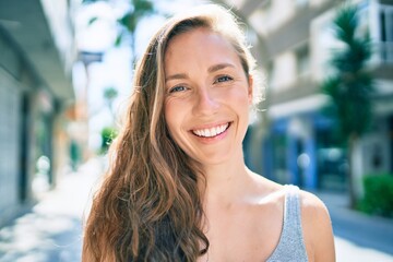 Young blonde woman smiling happy walking at street of city