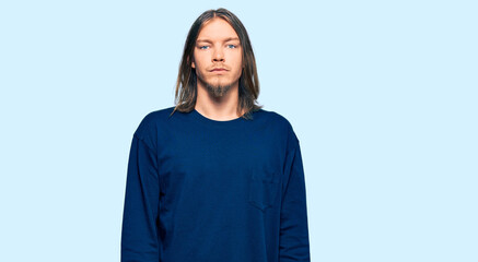 Fototapeta premium Handsome caucasian man with long hair wearing casual winter sweater relaxed with serious expression on face. simple and natural looking at the camera.