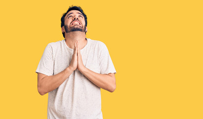 Young hispanic man wearing casual clothes begging and praying with hands together with hope expression on face very emotional and worried. begging.