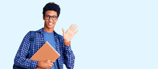 Young african american man wearing student backpack holding book waiving saying hello happy and...