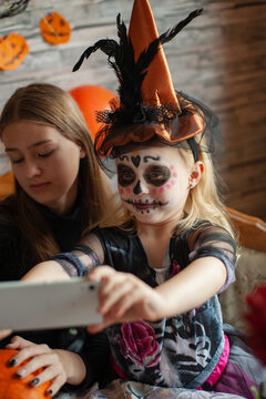 girl in skeleton costume with painted face makes funny selfie on phone