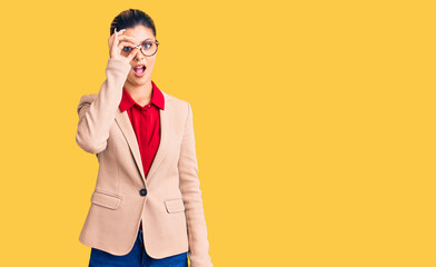 Young beautiful woman wearing business shirt and glasses doing ok gesture shocked with surprised face, eye looking through fingers. unbelieving expression.