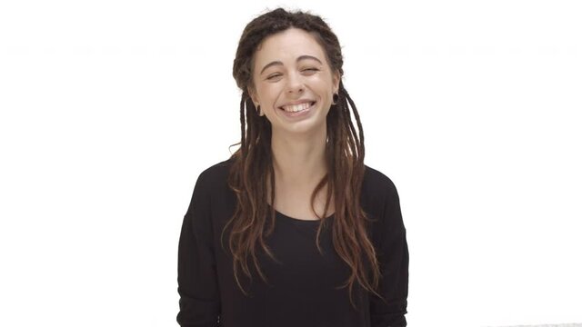 Beautiful hippie girl with dreadlocks and ear tunnels, wearing black blouse, looking up and daydreaming, laughing and looking cute, standing over white background
