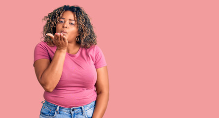 Young african american plus size woman wearing casual clothes looking at the camera blowing a kiss with hand on air being lovely and sexy. love expression.