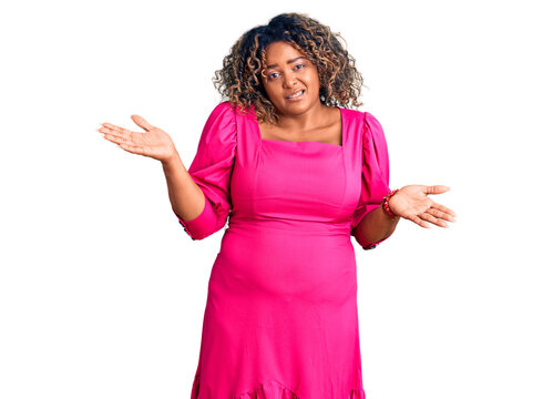 Young african american plus size woman wearing casual clothes clueless and confused expression with arms and hands raised. doubt concept.