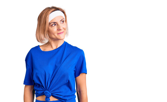 Young blonde woman wearing sportswear smiling looking to the side and staring away thinking.