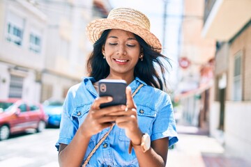Young indian woman smiling happy using smartphone at the city