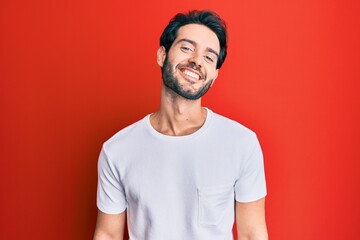 Young hispanic man wearing casual white tshirt with a happy and cool smile on face. lucky person.