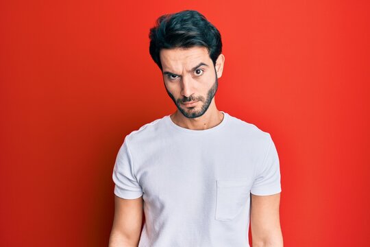Young hispanic man wearing casual white tshirt skeptic and nervous, frowning upset because of problem. negative person.