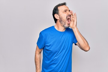 Middle age handsome man wearing casual t-shirt standing over isolated white background shouting and screaming loud to side with hand on mouth. Communication concept.