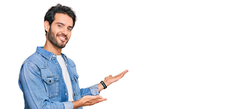 Young hispanic man wearing casual clothes inviting to enter smiling natural with open hand