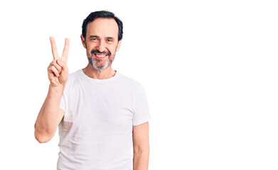 Fototapeta premium Middle age handsome man wearing casual t-shirt showing and pointing up with fingers number two while smiling confident and happy.