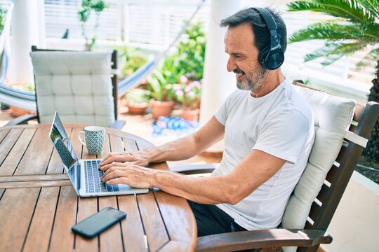 Middle Age Man With Beard Smiling Happy At The Terrace Working From Home Using Laptop
