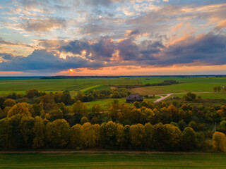 Aerial view of sunset and autumn colors trees in the fields with a house