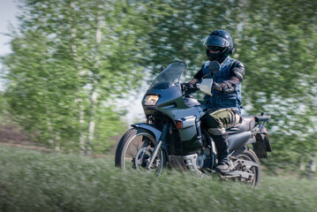 Biker is riding his motorbike on the countryside road.