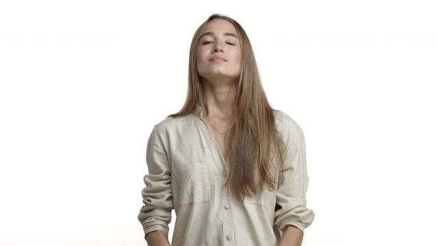 Video of attractive adult woman with long fair hair, wearing casual blouse, taking-off black face mask and breathing freely, smiling pleased, standing over white background