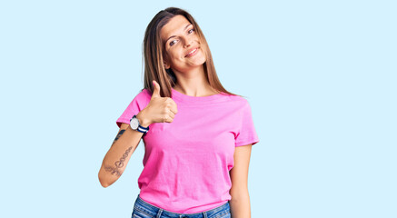 Beautiful caucasian woman wearing casual clothes doing happy thumbs up gesture with hand. approving expression looking at the camera showing success.