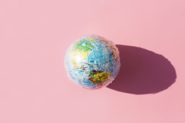 Planet Earth in wrap polyethylene plastic. The globe and global pollution by plastic. Minimal...