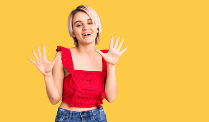 Young beautiful blonde woman wearing casual clothes showing and pointing up with fingers number ten while smiling confident and happy.