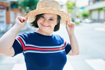 Beautiful brunette woman with down syndrome wearing a summer hat at the town on a sunny day