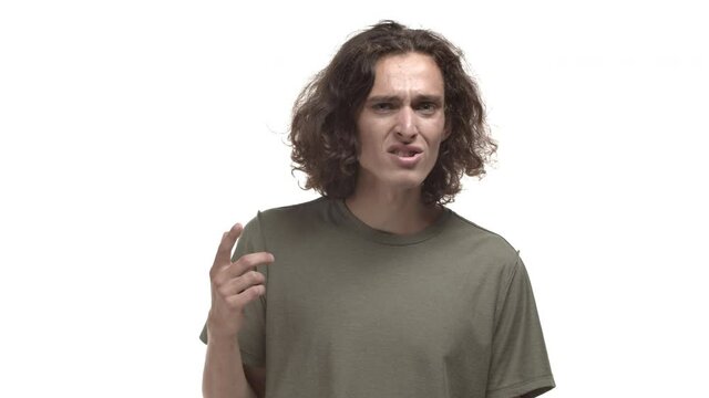 Handsome caucasian guy in casual t-shirt looking confused, cannot hear you, pointing at ear and asking to repeat question, standing over white background