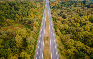Aerial view of autumn colors in the forest with highway crossing it