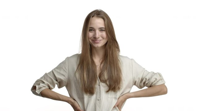 Video of pretty blond caucasian woman with teeth braces, looking suspicious and doubtful, raising eyebrow and starting to laugh and smile pleased, standing flirty over white background